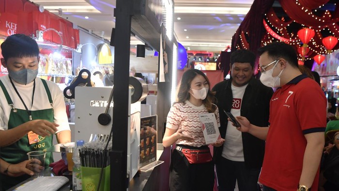 Kepo Market Surabaya Hadir Sambut Tahun Baru Imlek AVP SME Acquisition DOKU Herunata Joseph (kedua kanan) dan Founder Kepo Market Michael Putra Bani (kanan) berbincang dengan pengunjung yang sedang melakukan transaksi dengan menggunakan aplikasi dompet elektronik saat bazar kuliner Kepo Market di Surabaya, Jawa Timur, Sabtu (14/1/2023). Kepo Market yang disajikan dalam nuansa menyambut tahun baru Imlek tersebut menjadi wadah bagi pemilik bisnis UMKM untuk memasarkan produk mereka lebih luas ke konsumen dan DOKU menjadi opsi pembayaran non tunai melalui pindai QRIS. ANTARA FOTO/Zabur Karuru/foc.