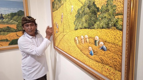 Pelukis Komang Bayu menunjukkan salah satu lukisannya yang dibuat dengan teknik pecut lidi saat pembukaan pameran tunggalnya sekaligus I Gusti Gede Aryadi Art Space, Rabu (11/1/2023).