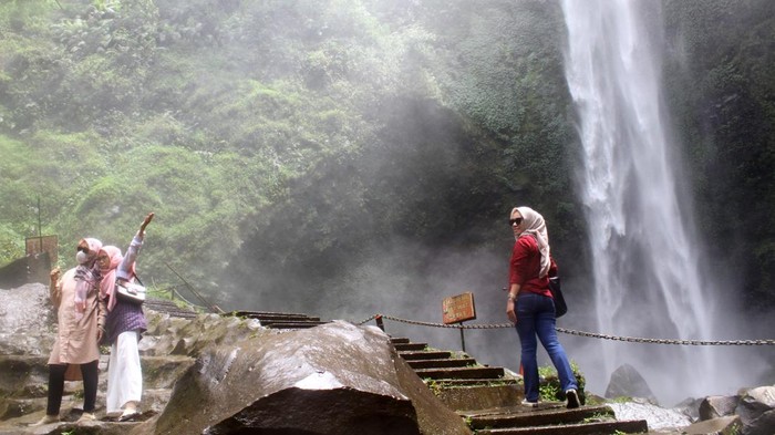 Sejumlah pengunjung menikmati pemandangan Air Terjun di Obyek Wisata Coban Rondo, Kecamatan Pujon, Kabupaten Malang, Jawa Timur, Sabtu (14/1/2023). Obyek wisata tersebut selain menawarkan keindahan panorama air terjun juga terdapat berbagai fasilitas wisata seperti camping ground, labirin, serta wisata petik buah strawberry. ANTARA FOTO/Bayu Pratama S/YU