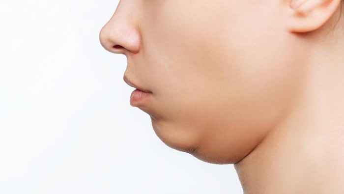 Cropped shot of a young caucasian womans face with double chin isolated on a white background. Overweight, flabby and sagging skin. Profile