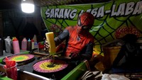 Seorang pria membuat kue sarang laba-laba dengan kostum Spiderman di Festival Grebeg Sudiro, Solo, Jawa Tengah, Sabtu (14/1/2023).