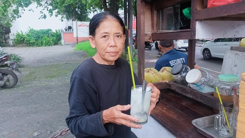Ayu, pedagang es kelapa muda mangkal di depan Kantor Lurah Kerobokan Kelod, Badung, pernah dapat uang sejuta gegara tolong bule haus. (Agus Eka)