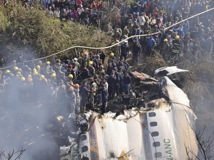 Bangkai pesawat Yeti Airlines yang jatuh di Nepal hancur, dengan petugas penyelamat dan warga sipil berkumpul di sekitarnya Nepalese rescue workers and civilians gather around the wreckage of a passenger plane that crashed in Pokhara, Nepal, Sunday, Jan. 15, 2023. Authorities in Nepal said 68 people have been confirmed dead after a regional passenger plane with 72 aboard crashed into a gorge while landing at a newly opened airport in the resort town of Pokhara. Its the countrys deadliest airplane accident in three decades. (AP Photo/Krishna Mani Baral)