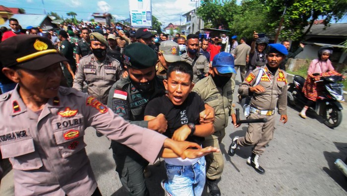 Petugas Satpol PP berusaha mengamankan salah satu pedagang saat akan dilakukan penertiban dan pembongkaran bangunan pedagang di Jalan Stadion Tunas Bangsa, Desa Mon Geudong, Lhokseumawe, Aceh, Senin (16/1/2023). Petugas gagal membongkar puluhan bangunan di kawasan itu karena adanya perlawanan dari para pedagang yang mayoritas ibu-ibu dan sempat bentrok dengan petugas. ANTARA FOTO/Rahmad/tom.