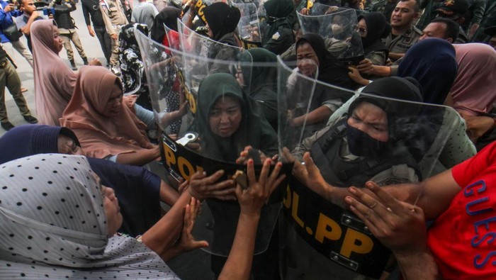 Petugas Satpol PP berusaha mengamankan salah satu pedagang saat akan dilakukan penertiban dan pembongkaran bangunan pedagang di Jalan Stadion Tunas Bangsa, Desa Mon Geudong, Lhokseumawe, Aceh, Senin (16/1/2023). Petugas gagal membongkar puluhan bangunan di kawasan itu karena adanya perlawanan dari para pedagang yang mayoritas ibu-ibu dan sempat bentrok dengan petugas. ANTARA FOTO/Rahmad/tom.