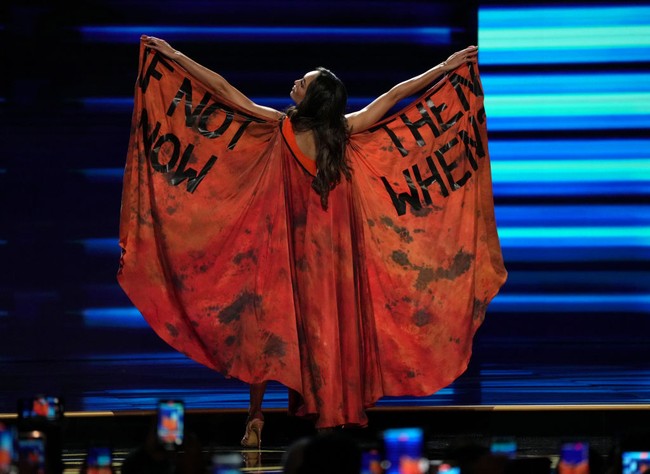 Cape yang dipakai R’Bonney Gabriel ini dihiasi tulisan ‘If Not Now, Then When?.” Kalimat dengan makna mendalam itu sudah lama dikampanyekan R’Bonney sebagai desainer dengan produk-produk ramah lingkungan. Foto: Getty Images