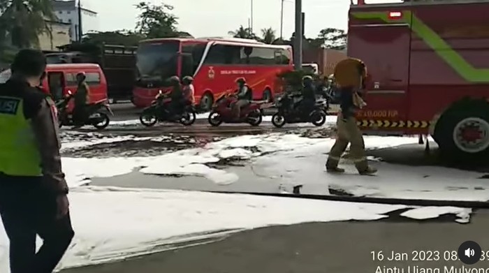 Petugas membersihkan jalan di Cilincing, Jakut, gara-gara terkena tumpahan oli.