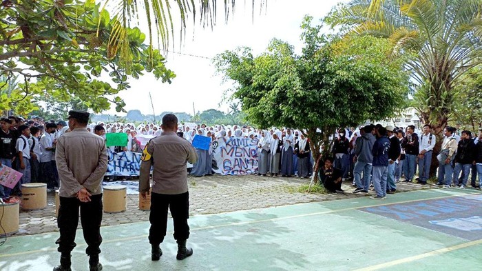 Polisi menenangkan siswa SMK Saintek Nurul Muslimin yang mengamuk, Senin (16/1/2023)