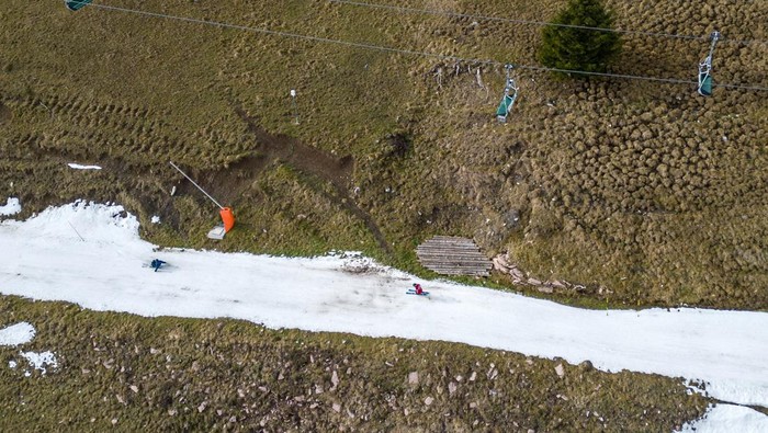 Potret Resor Ski di Swiss Kehilangan Salju Akibat Perubahan Iklim Skiers pass on a small layer of artificial snow amid warmer-than-usual winter temperatures in the Alps in Leysin, Switzerland, January 4, 2023. REUTERS/Denis Balibouse TPX IMAGES OF THE DAY