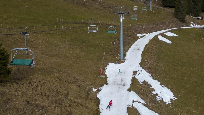 Skiers pass on a small layer of artificial snow amid warmer-than-usual winter temperatures in the Alps in Leysin, Switzerland, January 4, 2023. REUTERS/Denis Balibouse          TPX IMAGES OF THE DAY