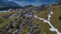 Para pemain ski melewati lapisan kecil salju buatan di tengah suhu musim dingin yang lebih hangat dari biasanya di Pegunungan Alpen di Leysin, Swiss, Rabu (4/1/2023).