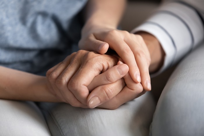 I know you can. Close up of millennial woman grown daughter, grandchild or younger friend holding tight hand of old mother, grandmother, elder relative or colleague helping to overpass life problems