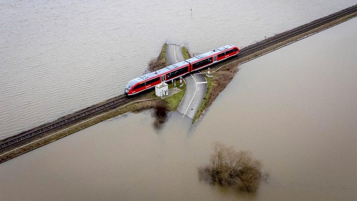 Banjir merendam kawasan Nidderau-Eichen, Frankfurt, Jerman, Senin (16/1/2023) waktu setempat. Namun sebuah kereta api tetap beroperasi meski kanan-kiri perlintasan terendam banjir.