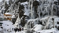 Turis menikmati air terjun beku di daerah Drang Tangmarh di Baramulla, India, Senin (16/1/2023).