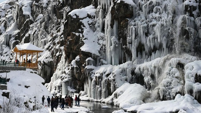Menikmati Air Terjun Membeku di India BARAMULLA, INDIA - JANUARY 16: Tourists enjoy near a frozen waterfall in the Drang area of Tangmarh on January 16, 2023 in Baramulla, India. The famous Drang waterfall next to Gulmarg has completely frozen due to minus temperatures. Snowfall in Kashmir had led to a high influx of tourists into the valley, especially at Drang in Gulmarg. Drang, a small village, is a beautiful tourist spot in the Tangmarg tehsil of Gulmarg, Baramulla. It is around 47 kilometres away from the capital city of Srinagar. The drive towards Drang although runs through a deep pine forest with the old mud houses around. (Photo by Waseem Andrabi/Hindustan Times via Getty Images)