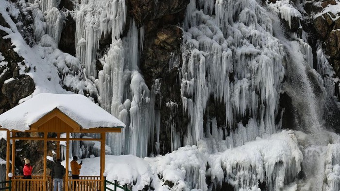 Menikmati Air Terjun Membeku di India BARAMULLA, INDIA - JANUARY 16: Tourists enjoy near a frozen waterfall in the Drang area of Tangmarh on January 16, 2023 in Baramulla, India. The famous Drang waterfall next to Gulmarg has completely frozen due to minus temperatures. Snowfall in Kashmir had led to a high influx of tourists into the valley, especially at Drang in Gulmarg. Drang, a small village, is a beautiful tourist spot in the Tangmarg tehsil of Gulmarg, Baramulla. It is around 47 kilometres away from the capital city of Srinagar. The drive towards Drang although runs through a deep pine forest with the old mud houses around. (Photo by Waseem Andrabi/Hindustan Times via Getty Images)