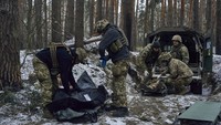 Petugas medis militer memberikan pertolongan pertama kepada tentara yang terluka (kanan) dan memasukkan jenazah tentara yang tewas ke dalam kantung jenazah.