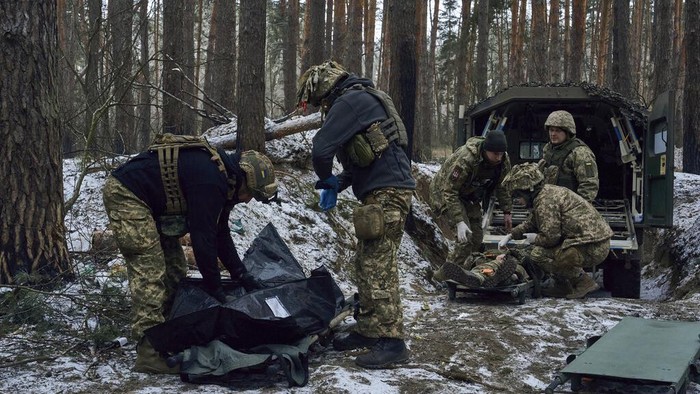 Potret Perjuangan Tentara Medis Ukraina di Medang Perang Military medics give first aid to a wounded soldier, right, and place the a body of a killed soldier into a bag, near Kremenna in the Luhansk region, Ukraine, Monday, Jan. 16, 2023. (AP Photo/LIBKOS)