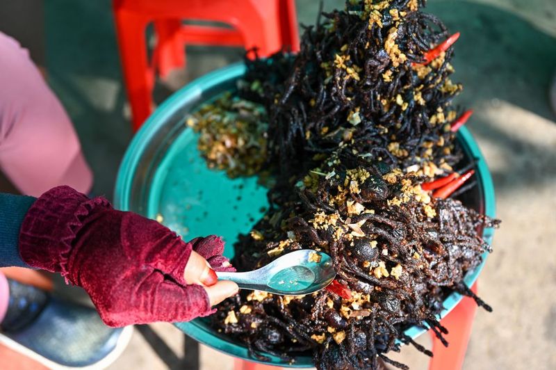 People buy fried tarantulas in the town of Skun in Kampong Cham province on January 15, 2023. (Photo by TANG CHHIN SOTHY / AFP) (Photo by TANG CHHIN SOTHY/AFP via Getty Images)