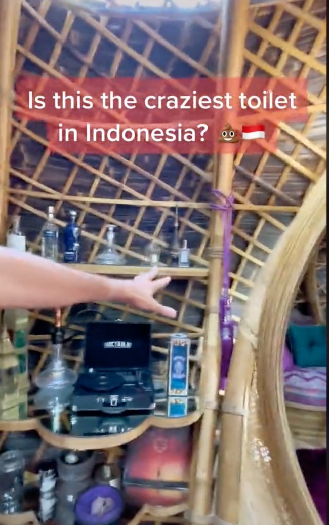 Di salah satu sisi toilet terdapat lemari pajangan yang terbuat dari kayu. Lemari pajangan tersebut berisi turntable atau pemutar piringan hitam, shisha, dan beberapa botol lainnya. Foto: TikTok/@traveltomtom