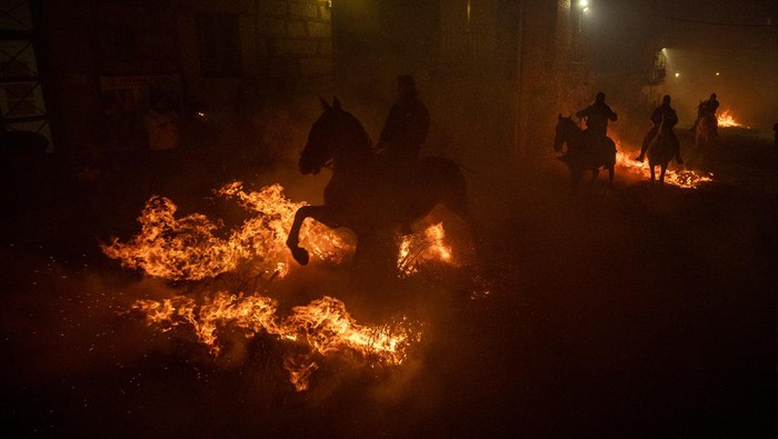 SAN BARTOLOME DE PINARES, SPAIN - JANUARY 16: People ride horses through bonfires during 'Las Luminarias' Festival on January 16, 2023 in San Bartolome de Pinares, Spain. In honour of Saint Anthony the Abbot, the patron saint of animals, horses are ridden through the bonfires on the night before the official day of celebrating animals in Spain. The tradition, which dates back to the time of the plague, is meant to purify and protect the animal in the coming year. (Photo by Pablo Blazquez Dominguez/Getty Images)