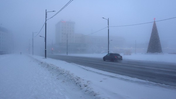 Sebuah mobil melaju di sepanjang jalan pada hari yang sangat dingin di Yakutsk, Rusia, Minggu (15/1/2023).  