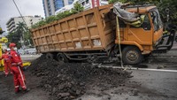 Badan truk yang mengalami kecelakaan menutup sebagian lajur jalan di Tol Dalam Kota. Muatan pasir juga terlihat tumpah di tepi jalan.  