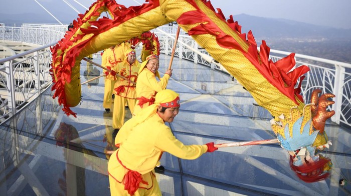 PINGJIANG, CHINA - JANUARY 17: Villagers perform lion dance on a glass skywalk alongside a cliff to greet Chinese New Year, the Year of the Rabbit, at the Shiniuzhai National Geological Park on January 17, 2023 in Pingjiang County, Yueyang City, Hunan Province of China. (Photo by Yang Huafeng/China News Service/VCG via Getty Images)