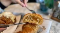 Tekstur pada plain croissantnya flaky, renyah tetapi lebih kokoh sehingga tidak mudah hancur saat dipotong. Rasanya yang buttery didukung dengan rongga honeycomb yang sempurna di dalamnya. Foto: Tim detikFood
