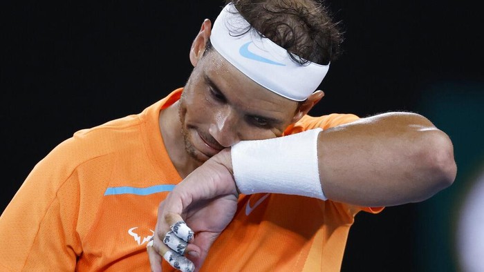 Ekspresi Rafael Nadal Kala Tersingkir dari Australia Open 2023 Rafael Nadal of Spain wipes the sweat from his face during his second round match against Mackenzie McDonald of the U.S., at the Australian Open tennis championship in Melbourne, Australia, Wednesday, Jan. 18, 2023. (AP Photo/Asanka Brendon Ratnayake)