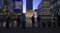 Orang-orang memotret instalasi Bumi Terapung karya Luke Jerram, sebagai bagian dari festival Winter Lights di Canary Wharf, London, Rabu (18/1/2023).