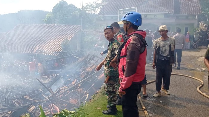 Petugas saat berusaha memadamkan api yang menghanguskan dua rumah di Tasikmalaya, Jumat (20/1/2023).