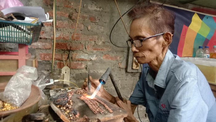 Maman perajin perhiasan emas imitasi di kampung kemasan Indramayu.