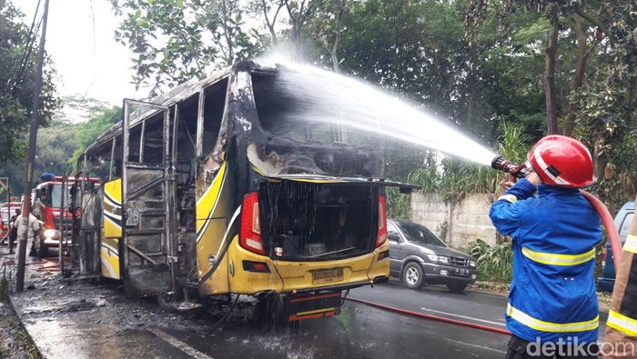 Petugas Damkar Boyolali menyemprotkan air ke bus yang terbakar, Sabtu (21/1/2023).