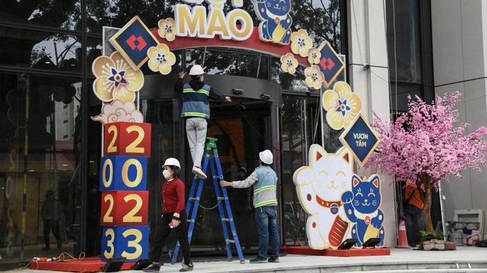 This photograph taken on January 16, 2023 shows workers decorating cat figures at a building entrance in Hanoi, ahead of the lunar new year. - As China gears up to welcome the Year of the Rabbit, the lunar new year looks slightly different in Vietnam -- where the Year of the Cat is about to begin. (Photo by Nhac NGUYEN / AFP) (Photo by NHAC NGUYEN/AFP via Getty Images)