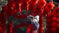 Seorang warga mengambil foto di sebuah taman yang didekorasi nuansa Imlek. 
