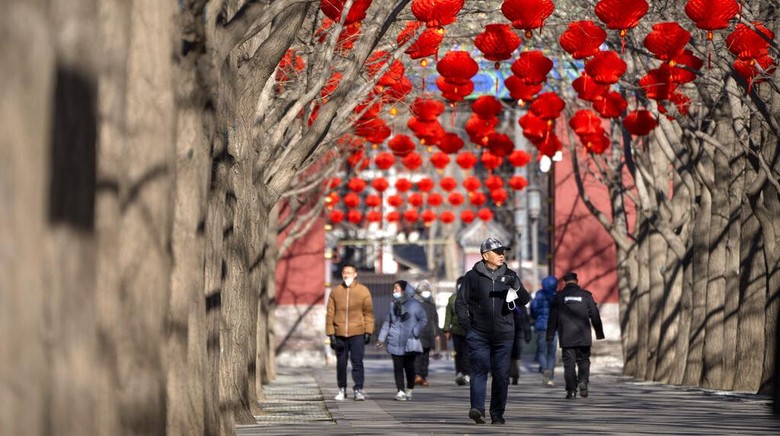People walk along a path decorated with lanterns for the upcoming Lunar New Year at a public park in Beijing, Friday, Jan. 20, 2023. The Year of the Rabbit officially begins on Jan. 22. (AP Photo/Mark Schiefelbein)