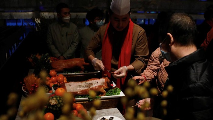 A staff member serves food to a table during a Lunar New Year's Eve dinner service at Shangri-La Shougang Park hotel in Beijing, China, January 21, 2023. REUTERS/Florence Lo