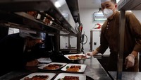 Seorang koki menyiapkan hidangan untuk makan malam Tahun Baru Imlek.  