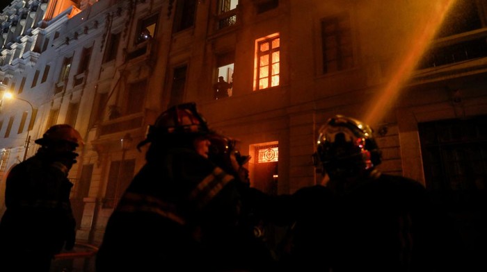Protes Peru Meluas, Bangunan di Ibu Kota Lima Hangus Terbakar Emergency service members work following a fire on top of a building during the 'Take over Lima' march to demonstrate against Peru's President Dina Boluarte, following the ousting and arrest of former President Pedro Castillo, in Lima, Peru January 19, 2023. REUTERS/Alessandro Cinque