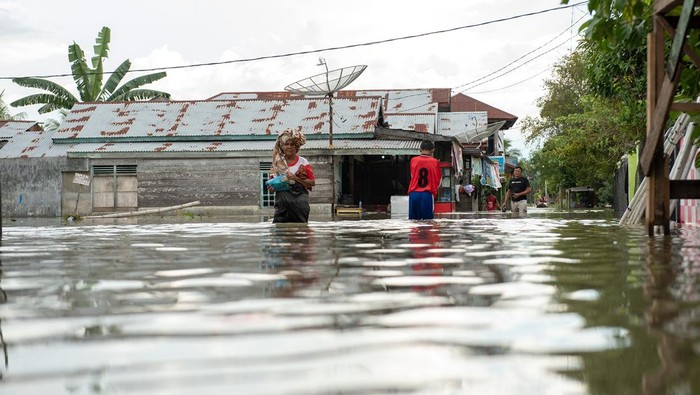 Sejumlah warga melintasi banjir yang melanda Kampung Tibang, Kecamatan Pidie, Kabupaten Pidie, Aceh, Minggu (22/1/2023). Banjir tersebut disebabkan tingginya intensitas hujan di kawasan tersebut dan buruknya drainase. ANTARA FOTO/Joni Saputra/Lmo/rwa.