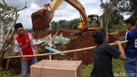 Sejumlah ahli waris dan petugas melakukan relokasi makam.