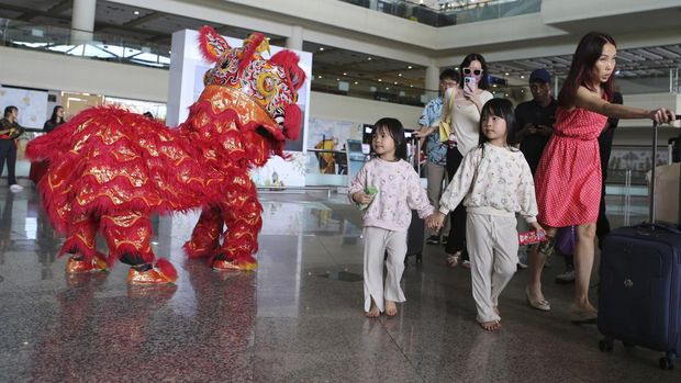 A lion dancer welcomes Chinese tourists on their arrival at Ngurah Rai international airport in Bali, Indonesia on Sunday, Jan. 22, 2023. A direct flight from China landed in Indonesia's resort island of Bali for the first time on Sunday in nearly three years after the route was cancelled due to the pandemic. (AP Photo/Firdia Lisnawati)
