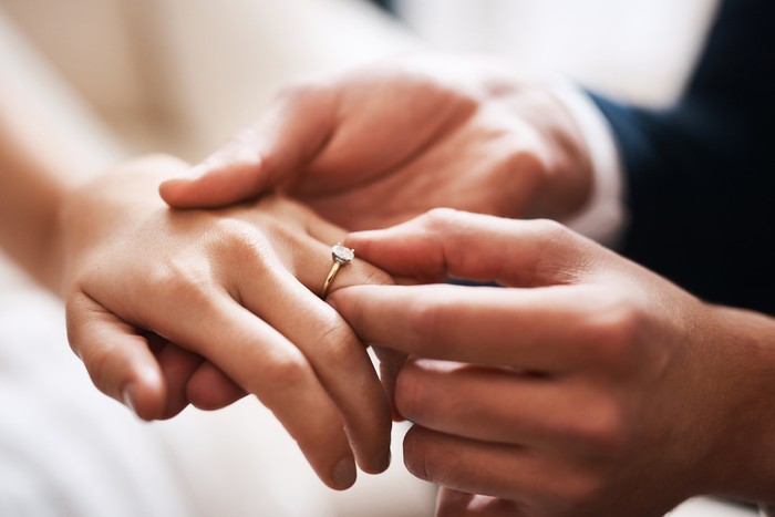 Cropped shot of an unrecognizable groom putting a diamond ring on his wifes finger during their wedding