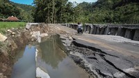 Pengendara sepeda motor melintas di jalan penghubung desa yang amblas di Sriharjo, Bantul, DI Yogyakarta, Senin (23/1/2023).