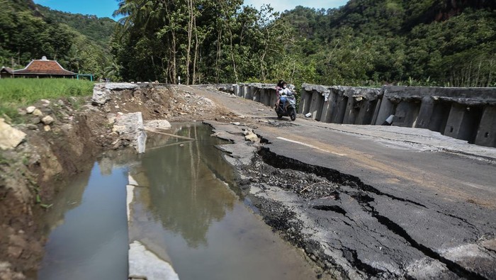 JALAN PENGHUBUNG DESA WISATA AMBLAS Pengendara sepeda motor melintas di jalan penghubung desa yang amblas di Sriharjo, Bantul, DI Yogyakarta, Senin (23/1/2023). Jalan penghubung desa wisata Sriharjo dengan Selopamioro yang sudah beberapa kali diperbaiki itu amblas, dan rencananya Pemkab Bantul akan bekerja sama dengan pakar geologi untuk melakukan berbaikan jalan tersebut. ANTARA FOTO/Hendra Nurdiyansyah/tom.
