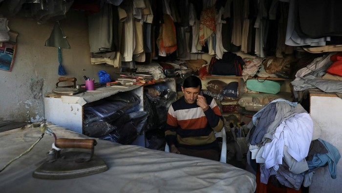 Pakistan Gelap Gulita Gegara Pemadaman Listrik Satu Negara A laundryman uses cell phone as he sits at his shop during country-wide power breakdown in Peshawar, Pakistan January 23, 2023. REUTERS/Fayaz Aziz