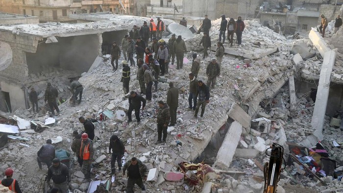 In this photo provided by Kurdish-run Hawar News Agency, civil defense workers and civilians work on the rubble of a destroyed building in the Sheikh Maksoud neighborhood in Aleppo, Syria, Sunday, Jan. 22, 2023. The building collapsed in Aleppo early Sunday, killing at least 10 people, Syrian state media reported. (Hawar News Agency via AP)