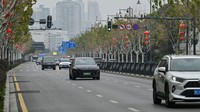 Gabungan gambar menunjukkan (atas) foto seorang pria mengendarai sepeda motor di jalan kosong di Wuhan pada 26 Januari 2020, dan (bawah) pemandangan yang sama di Wuhan pada 21 Januari 2023.
