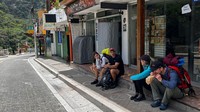 Turis menunggu di luar stasiun kereta Machu Picchu setelah layanan kereta api dihentikan karena kerusakan yang diduga disebabkan oleh pengunjuk rasa di Machu Picchu, Peru, Sabtu (21/1/2023).  